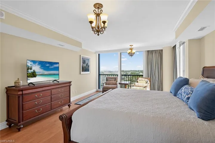 Bedroom with hanging lights, floor to ceiling windows, ornamental molding, access to exterior, and wood finished floors