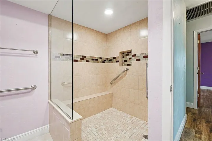 The stand-up shower is HUGE! With a tiled bench seat & gorgeous custom glass tile inlay
