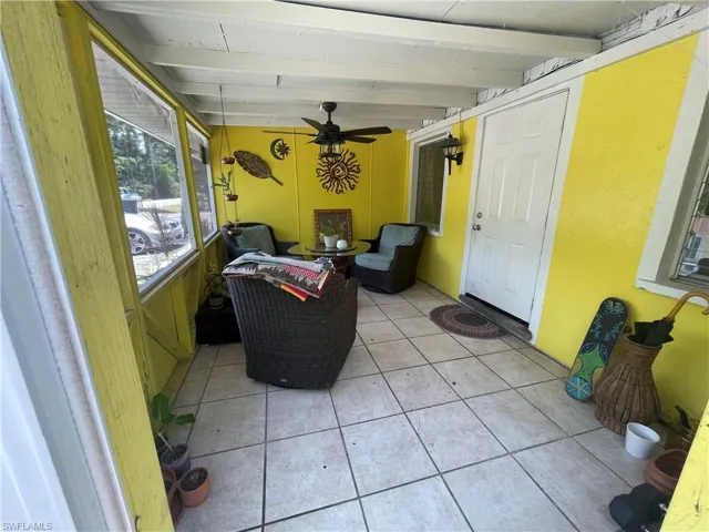Sunroom / solarium featuring beamed ceiling and ceiling fan