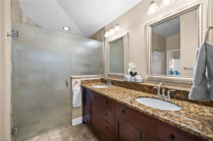 Spacious primary bath with dual sinks & expanded glass-enclosed shower.