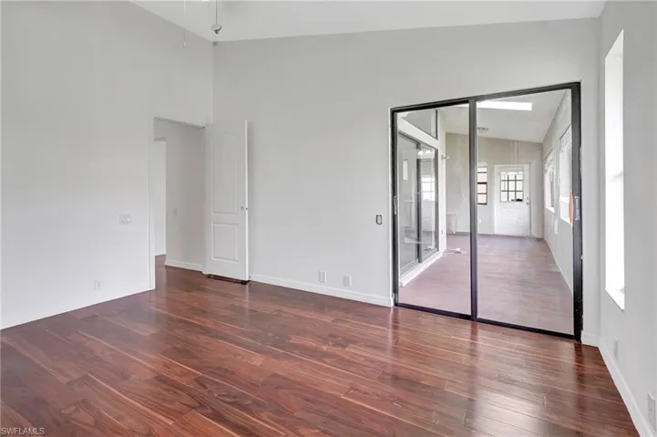 Unfurnished bedroom with lofted ceiling, a closet, and dark hardwood / wood-style flooring