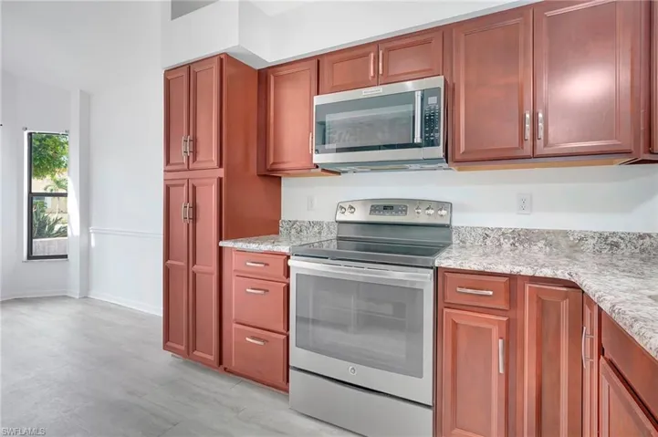 Kitchen with appliances with stainless steel finishes and light stone counters
