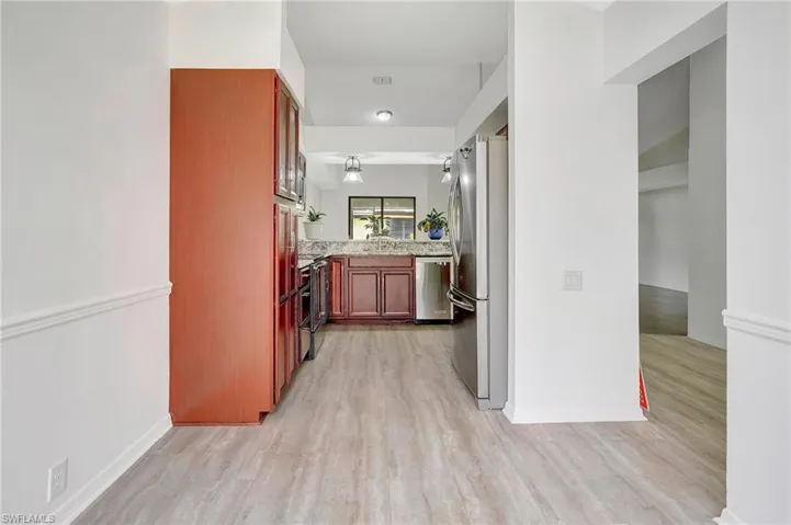 Kitchen with light wood-type flooring, light stone countertops, stainless steel appliances, and sink