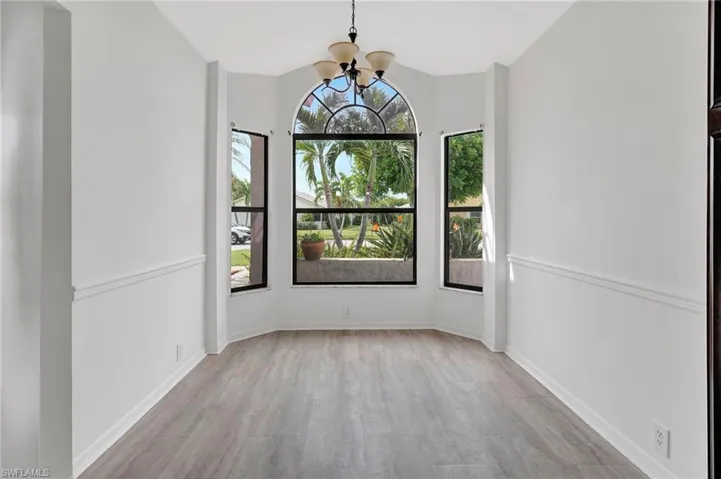 Unfurnished dining area with an inviting chandelier and light hardwood / wood-style floors