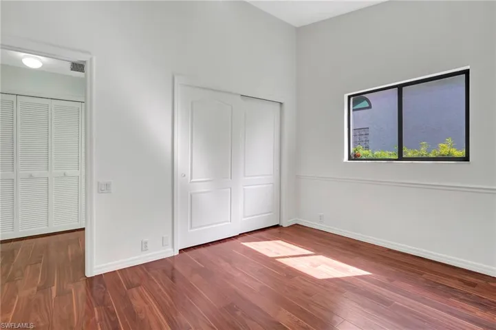 Unfurnished bedroom with dark hardwood / wood-style flooring and a closet