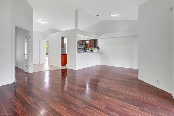 Unfurnished living room with vaulted ceiling and dark hardwood / wood-style flooring
