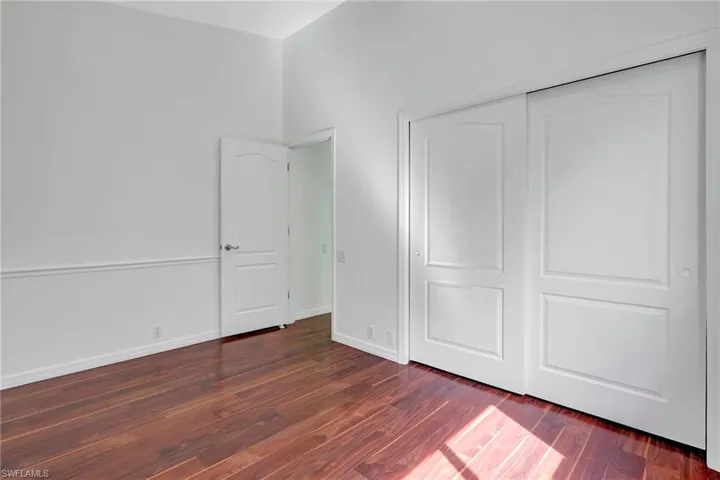 Unfurnished bedroom with dark wood-type flooring and a closet