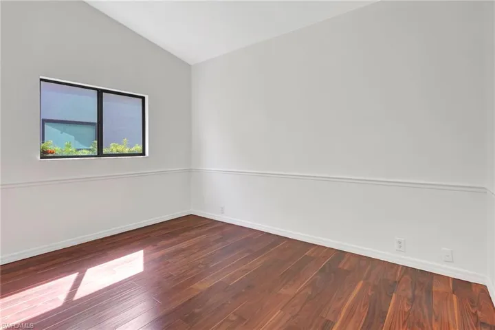 Unfurnished room with vaulted ceiling and dark hardwood / wood-style floors