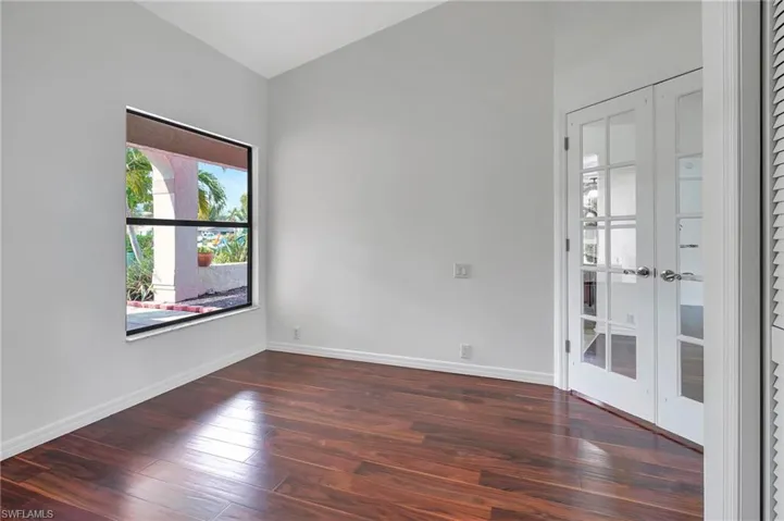 Unfurnished room with dark wood-type flooring and french doors