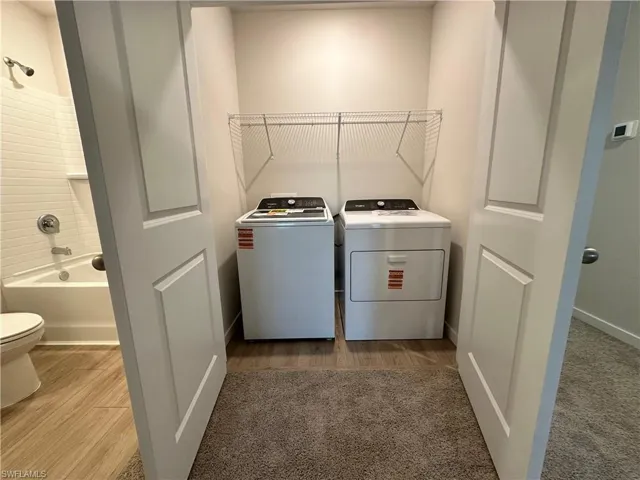 Laundry area with washer and clothes dryer and light wood-style flooring