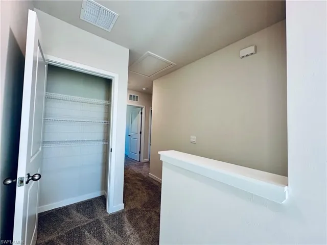 Hall featuring dark carpet and baseboards