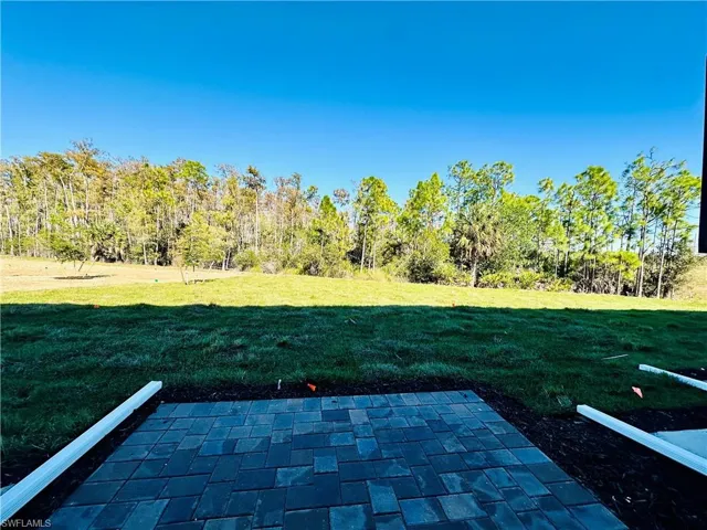 View of grassy yard featuring a patio area