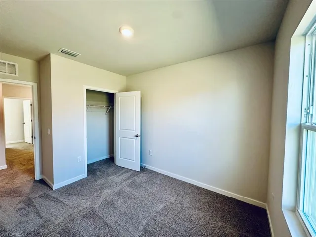 Unfurnished bedroom featuring carpet flooring, a closet, and multiple windows