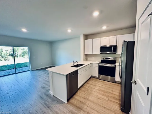 Kitchen featuring stainless steel appliances, white cabinetry, light wood finished floors, a peninsula, and recessed lighting