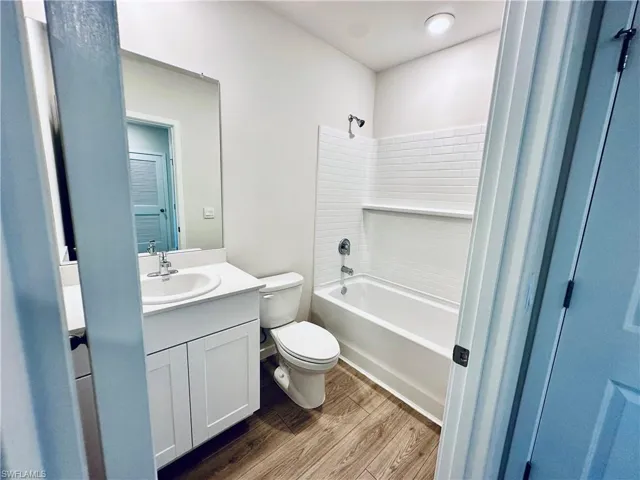 Full bathroom featuring vanity, bathtub / shower combination, and dark wood-type flooring