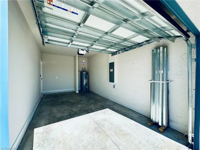 Garage with concrete block wall, electric panel, and water heater