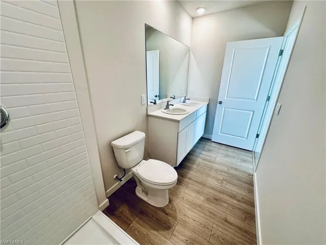 Full bathroom with double vanity and light wood-style floors