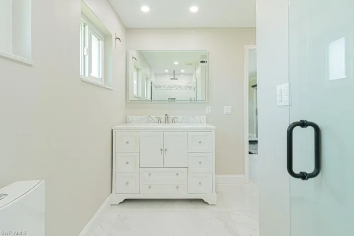 Bathroom with vanity, light marble finish floors, a shower stall, and recessed lighting