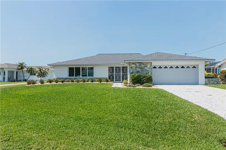 Ranch-style house with a front yard, decorative driveway, stucco siding, a garage, and stone siding