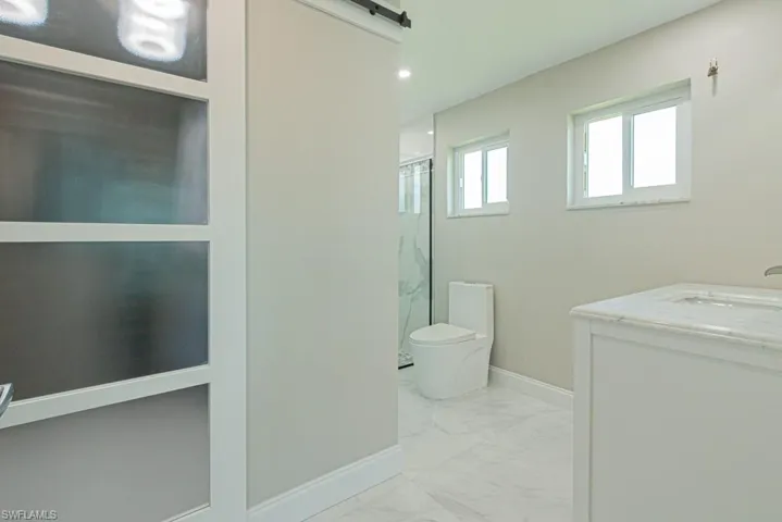 Full bath with light marble finish flooring, vanity, a marble finish shower, and recessed lighting