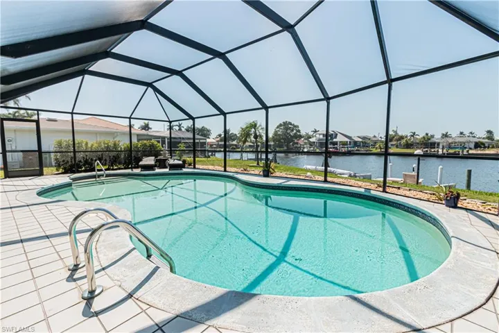 Swimming pool featuring glass enclosure, a sunroom, a water view, a patio, and a residential view
