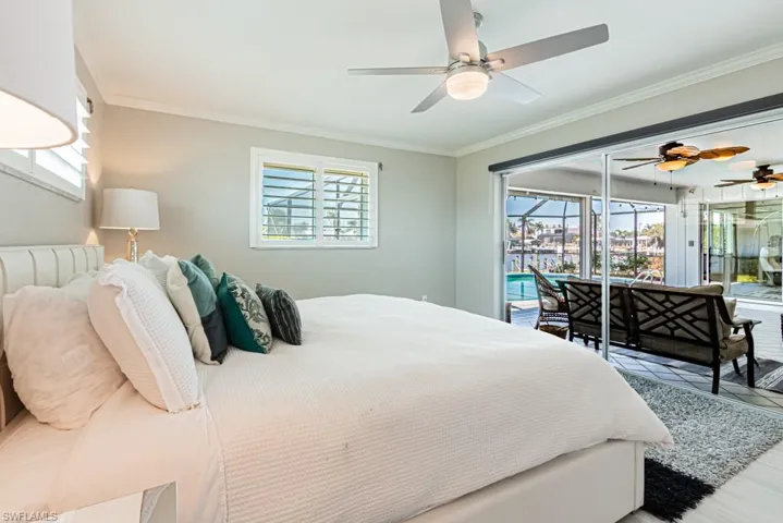 Bedroom featuring a sunroom, ornamental molding, access to outside, and wood finished floors