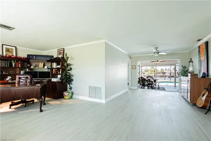 Office area with a sunroom, crown molding, light wood-style flooring, and a ceiling fan