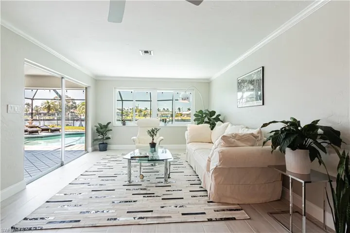 Living area featuring ornamental molding, a sunroom, ceiling fan, and light wood-type flooring