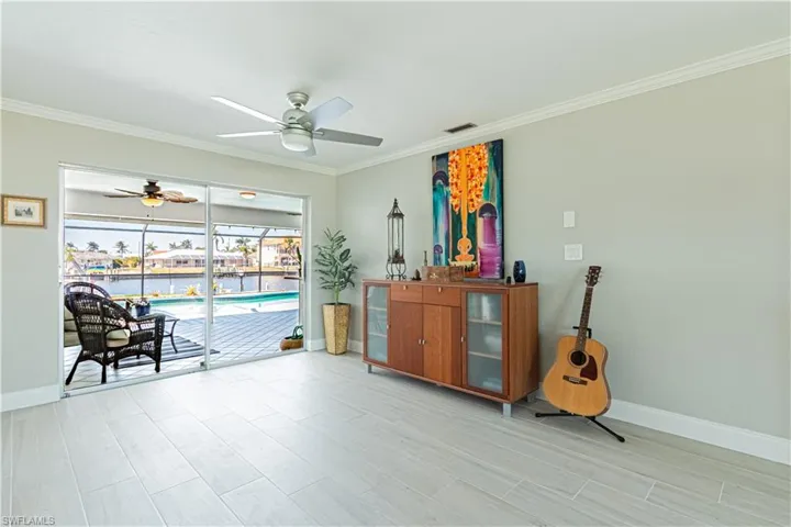 Sitting room featuring ornamental molding, wood finish floors, a sunroom, a water view, and a ceiling fan