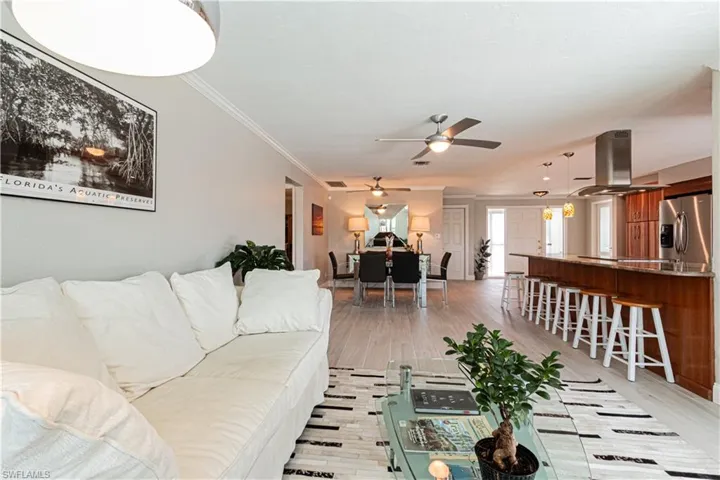 Living area featuring ornamental molding, light wood finished floors, and a ceiling fan