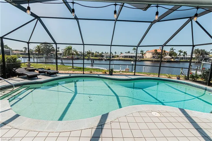 Outdoor pool featuring a sunroom, glass enclosure, and a water view