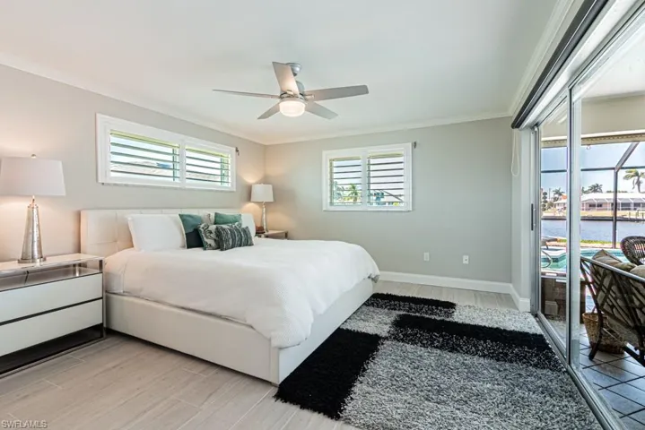 Bedroom with access to outside, a water view, crown molding, wood tiled floors, and ceiling fan