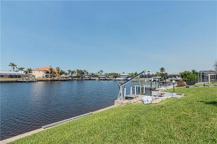 Dock featuring boat lift, a yard, and a water view