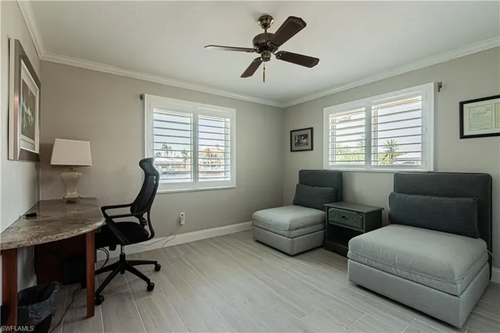 Office space featuring crown molding, healthy amount of natural light, light wood-style flooring, and ceiling fan