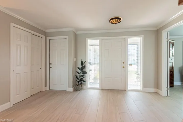 Entryway featuring crown molding and light wood finished floors