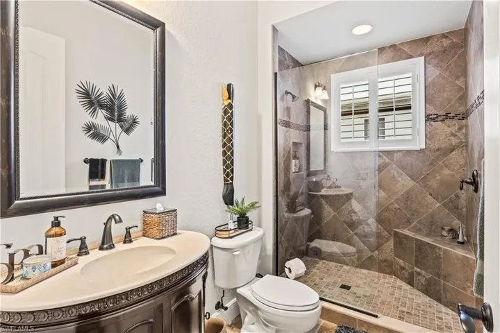 Guest Bathroom featuring toilet, vanity, and tiled shower