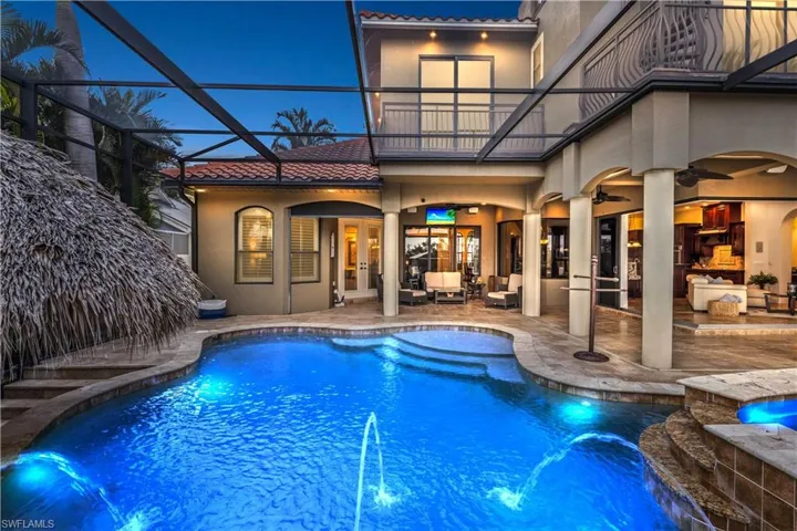 Straight out of a magazine - this resort style backyard offers everything!! A huge custom pool with built in chairs around a sunken tiki bar, a ten person spa, multiple outdoor living areas and sliders that open the inside and outside to blend seamlessly into everything that personifies the best of SWFL luxury living!