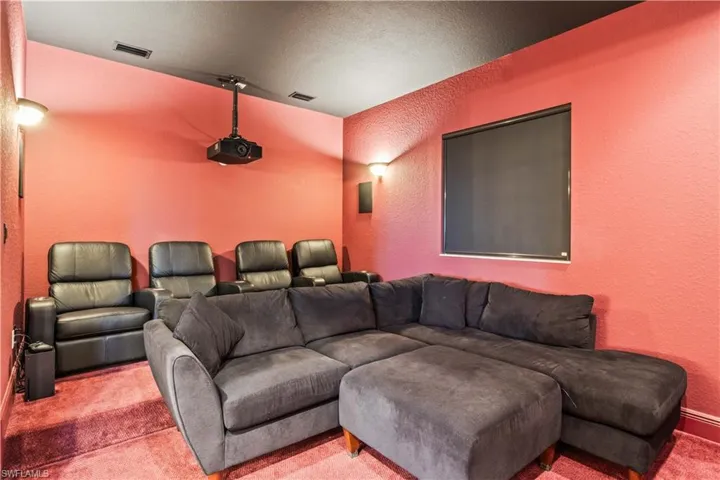 Cinema room featuring lofted ceiling, light colored carpet, and a textured ceiling