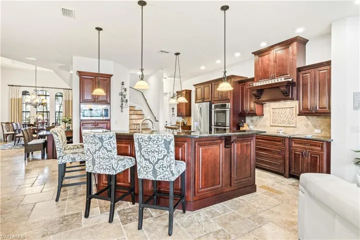 Expanded view of the kitchen - looking towards the front of the home and the bar and dining area.  Beautiful backsplash, granite counters and craftsman cabinets!