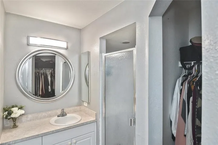 Full bathroom featuring a walk in closet, a stall shower, and vanity