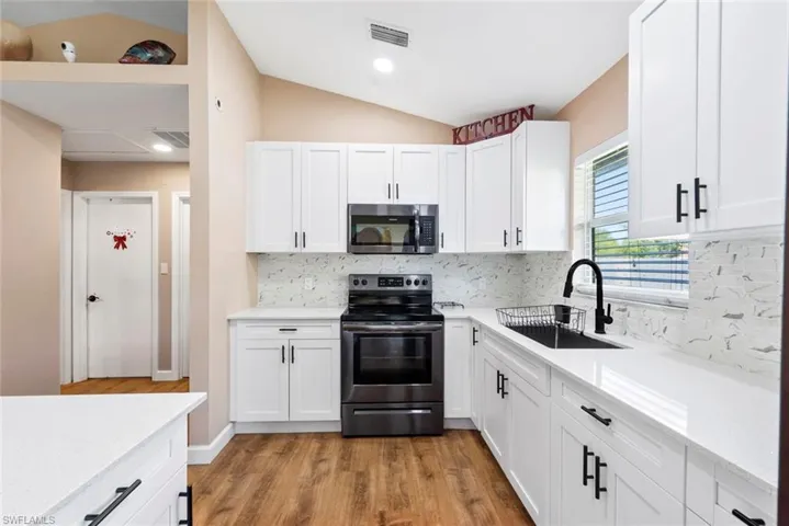 Kitchen featuring white shaker cabinetry, stainless steel appliances, white countertops, and wood-finish flooring
