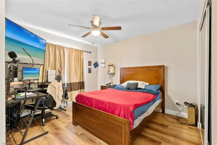 Wood-finish flooring, ceiling fan with integrated lighting, window with drapes, and built-in closet with sliding doors