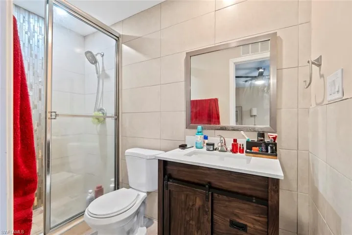 Bathroom featuring a glass-enclosed shower, wood-finish vanity with countertop, and a wall-mounted mirror