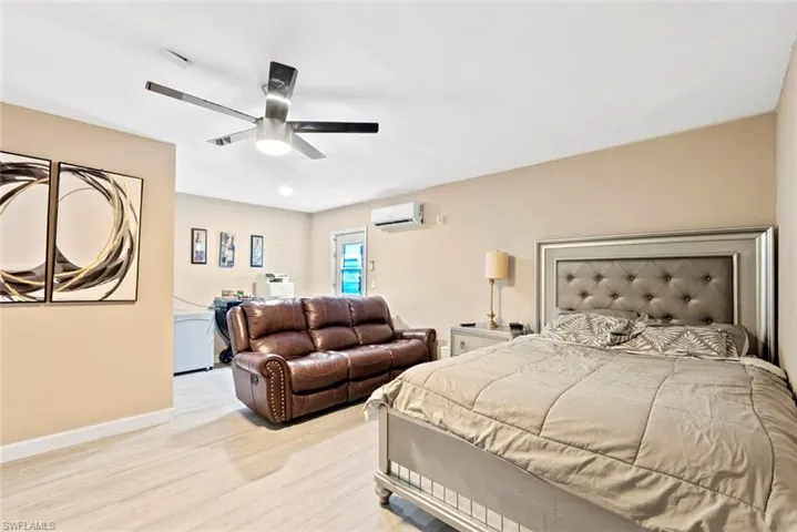 Light wood-finish flooring, ceiling fan with integrated lighting, wall-mounted air conditioning unit, recessed ceiling lighting
