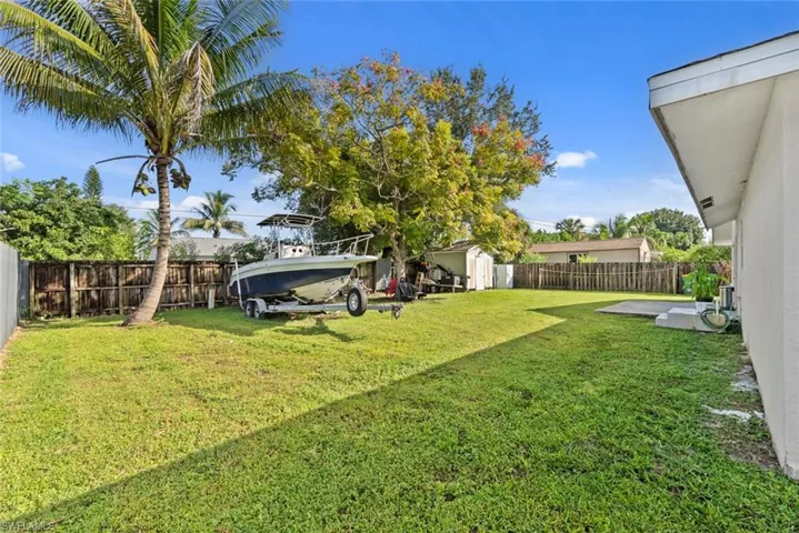 Expansive lawn area with mature trees and a privacy fence