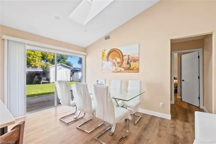 Sliding glass door, wood-finish flooring, recessed lighting, vaulted ceiling, and an expansive backyard