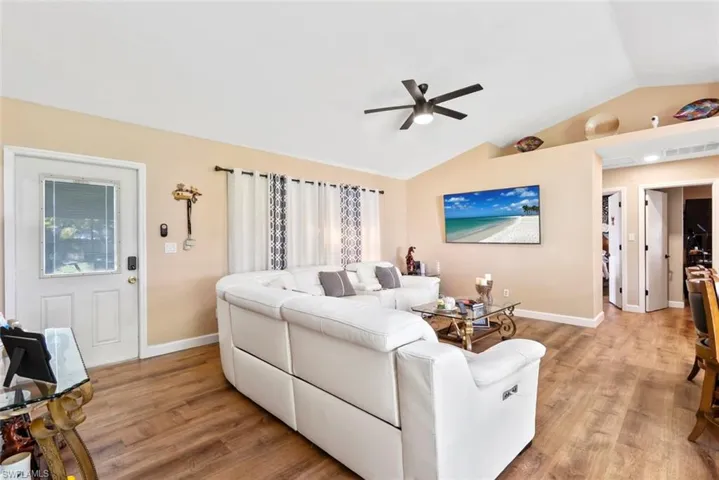 Vaulted ceilings with a ceiling fan, wood-finish flooring, and light-toned walls