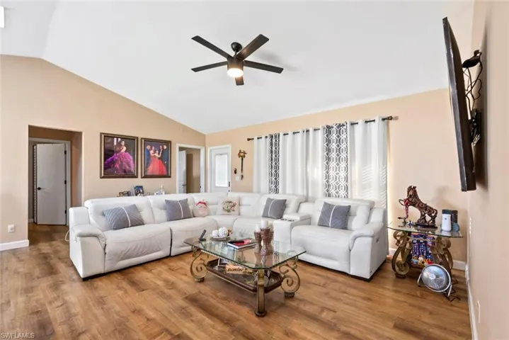 Vaulted ceiling with a ceiling fan, wood-finish flooring, and recessed doorways