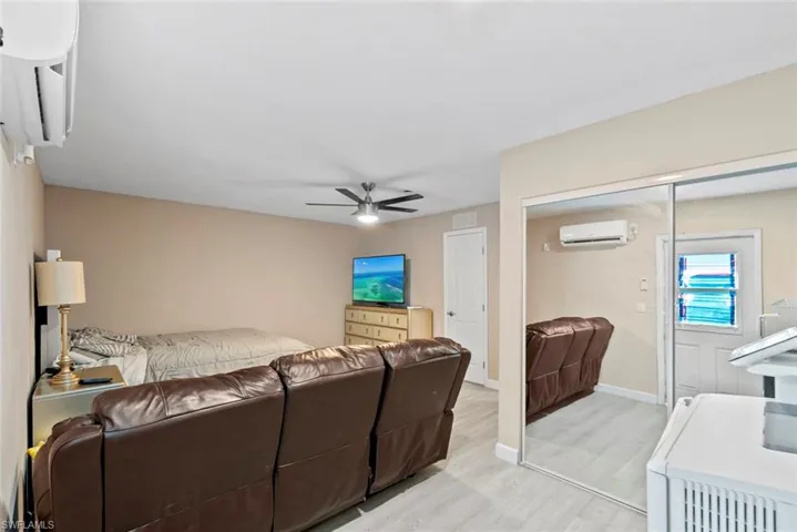 Split-unit air conditioning system, light wood-finish flooring, ceiling fan with integrated lighting, and mirrored closet doors