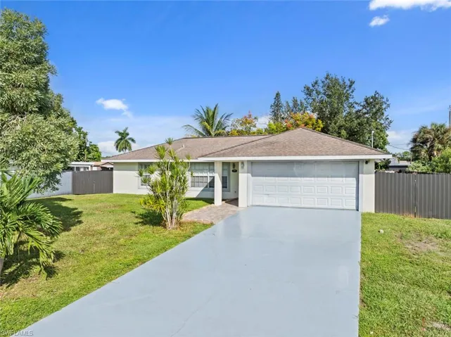 Single-story residence with an attached garage, paved driveway, and mature landscaping